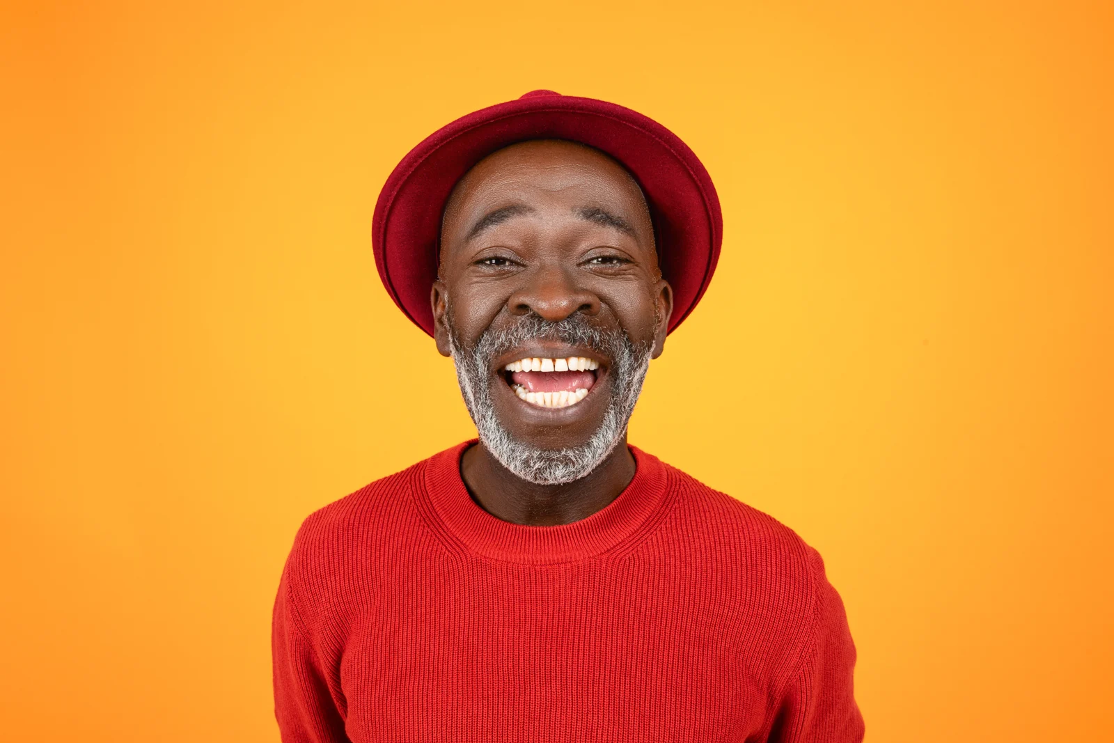 A smiling man in a red hat against orange