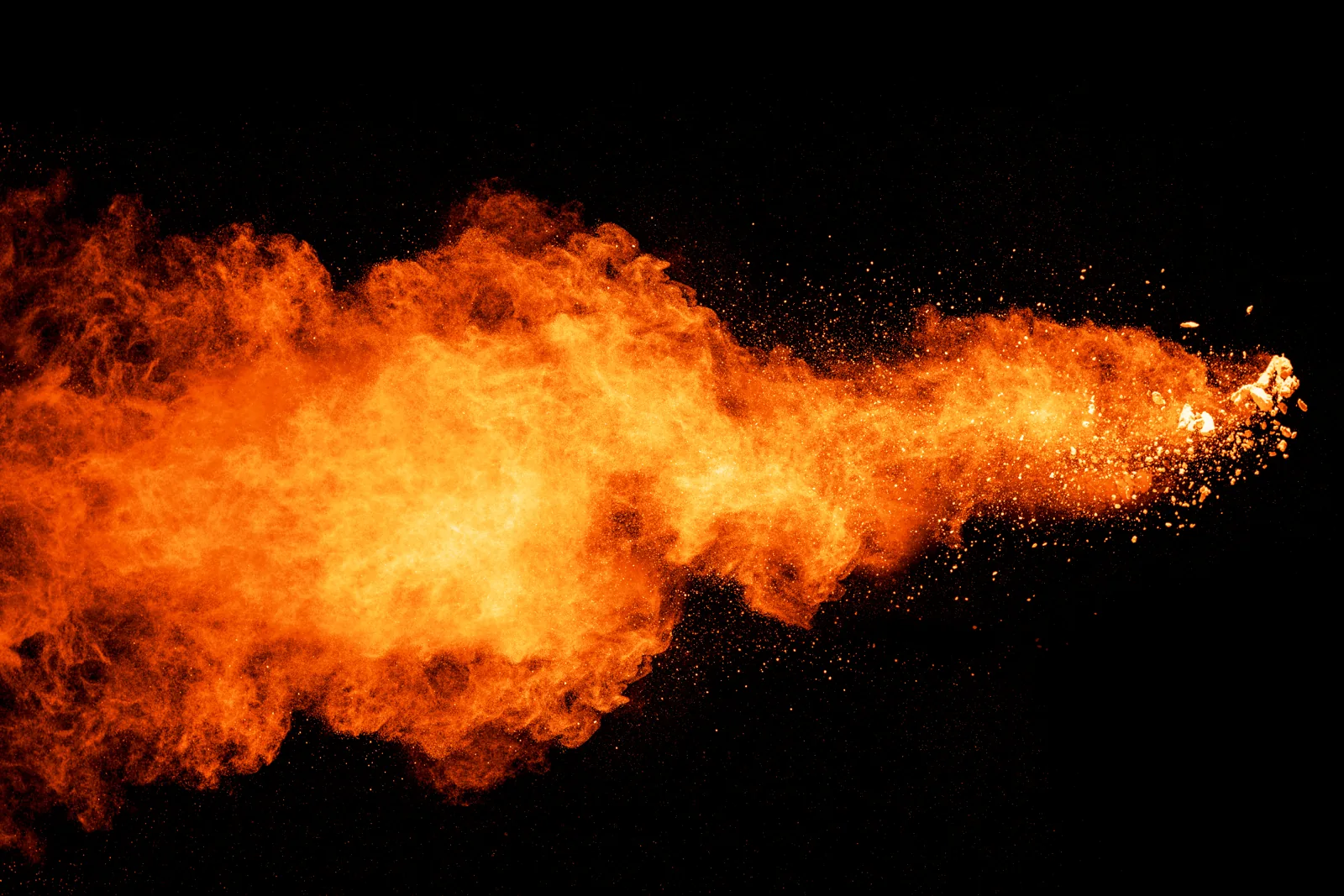 Orange pigment exploding across a black background