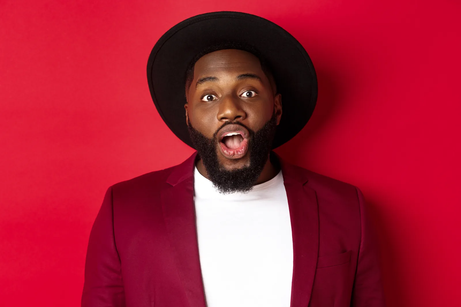An expressive portrait against a vivid red background