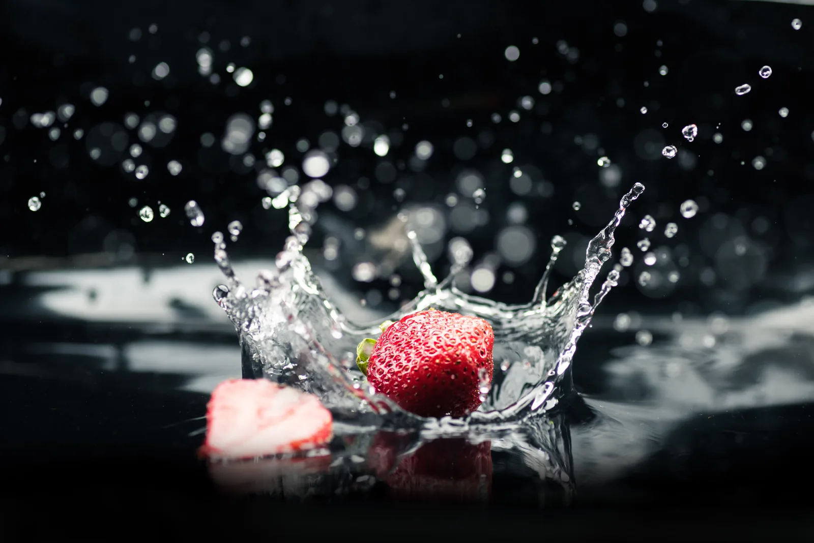 A strawberry creating a splash in dark water