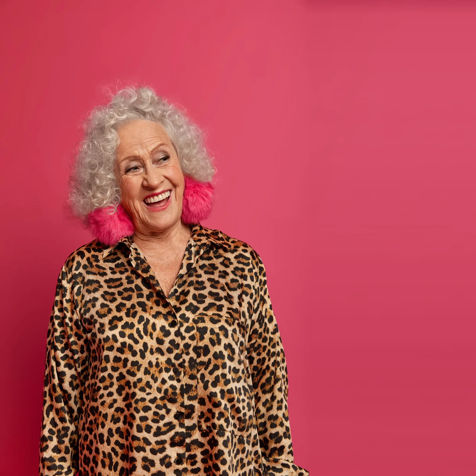 A laughing woman in leopard print against pink